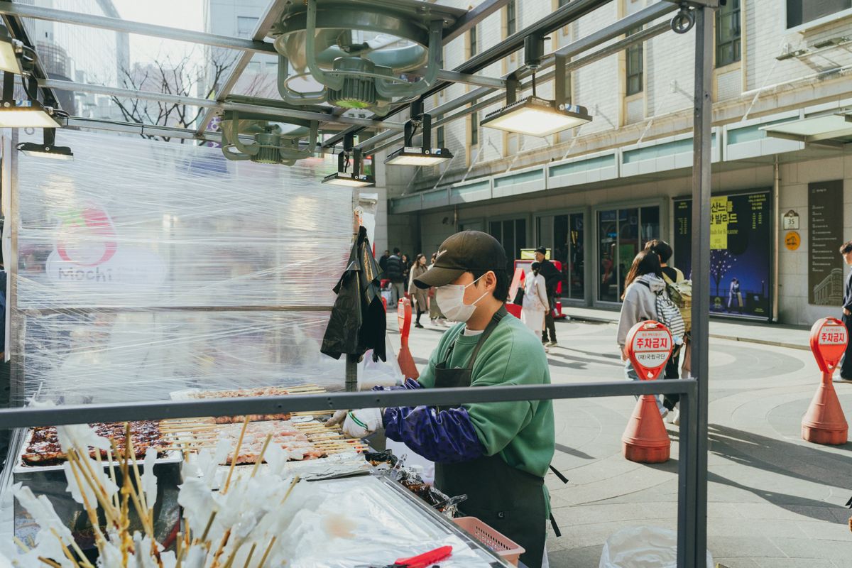 A Seoul street snack scene near a busy city center, showing how food stalls attach themselves to foot traffic.
