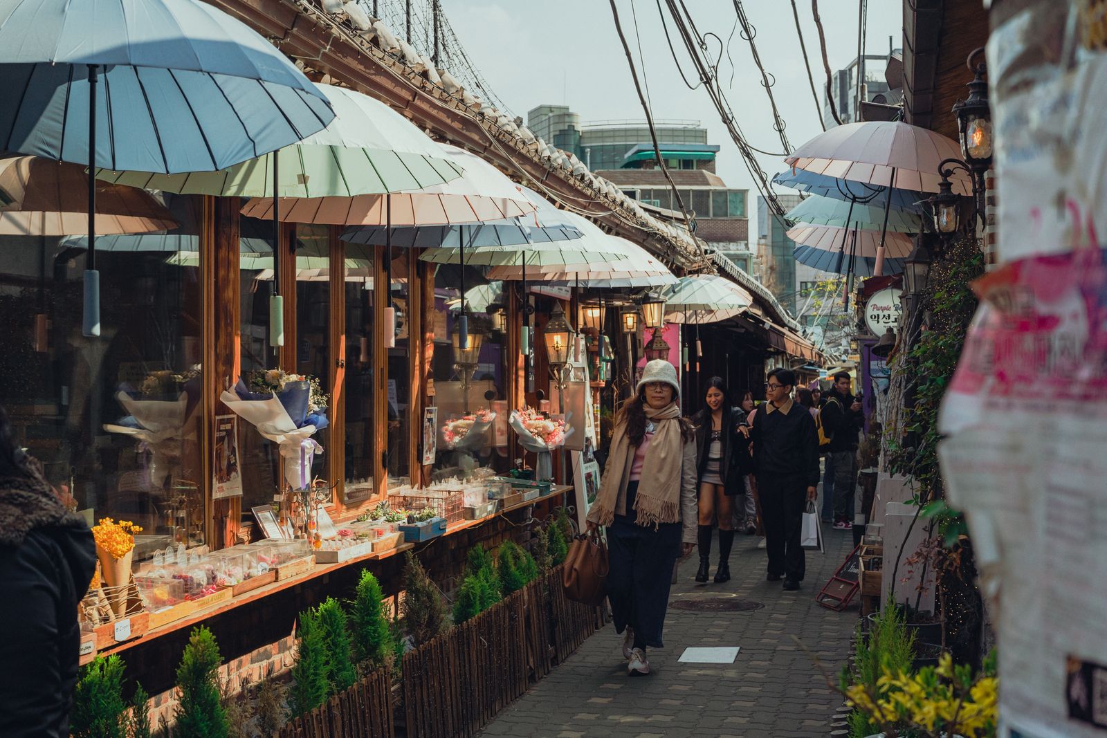 A Seoul market lane with umbrella cover and shopfronts, showing why rainy-day routing should stay compact.