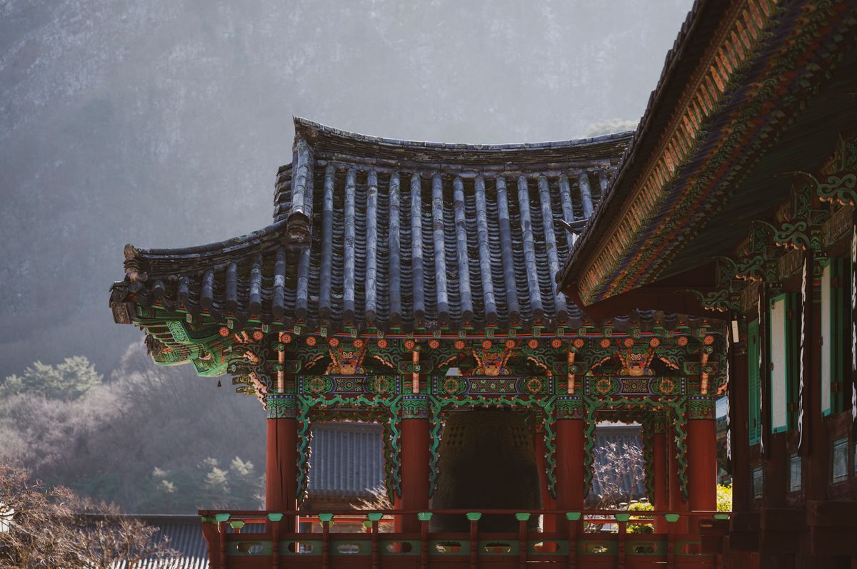Traditional Korean temple roof detail in a mountain setting.