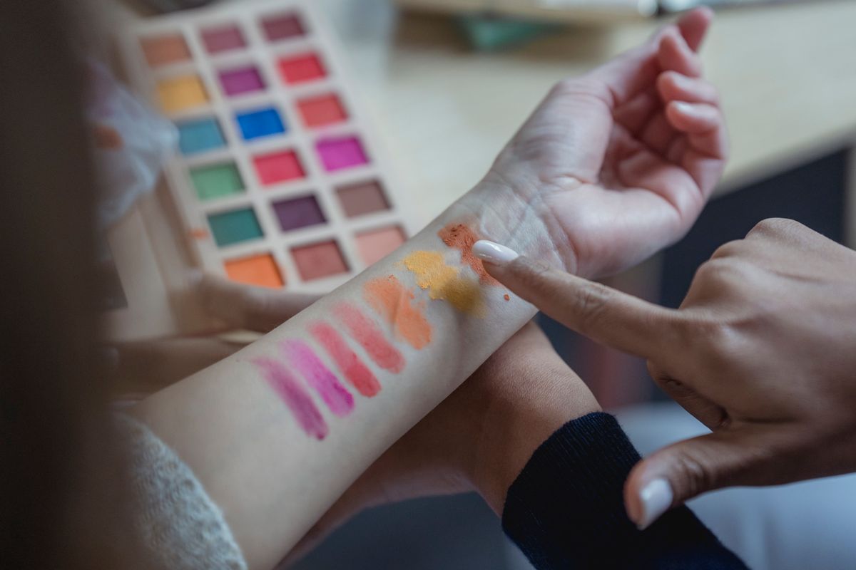A makeup artist testing several color shades on a client's arm.