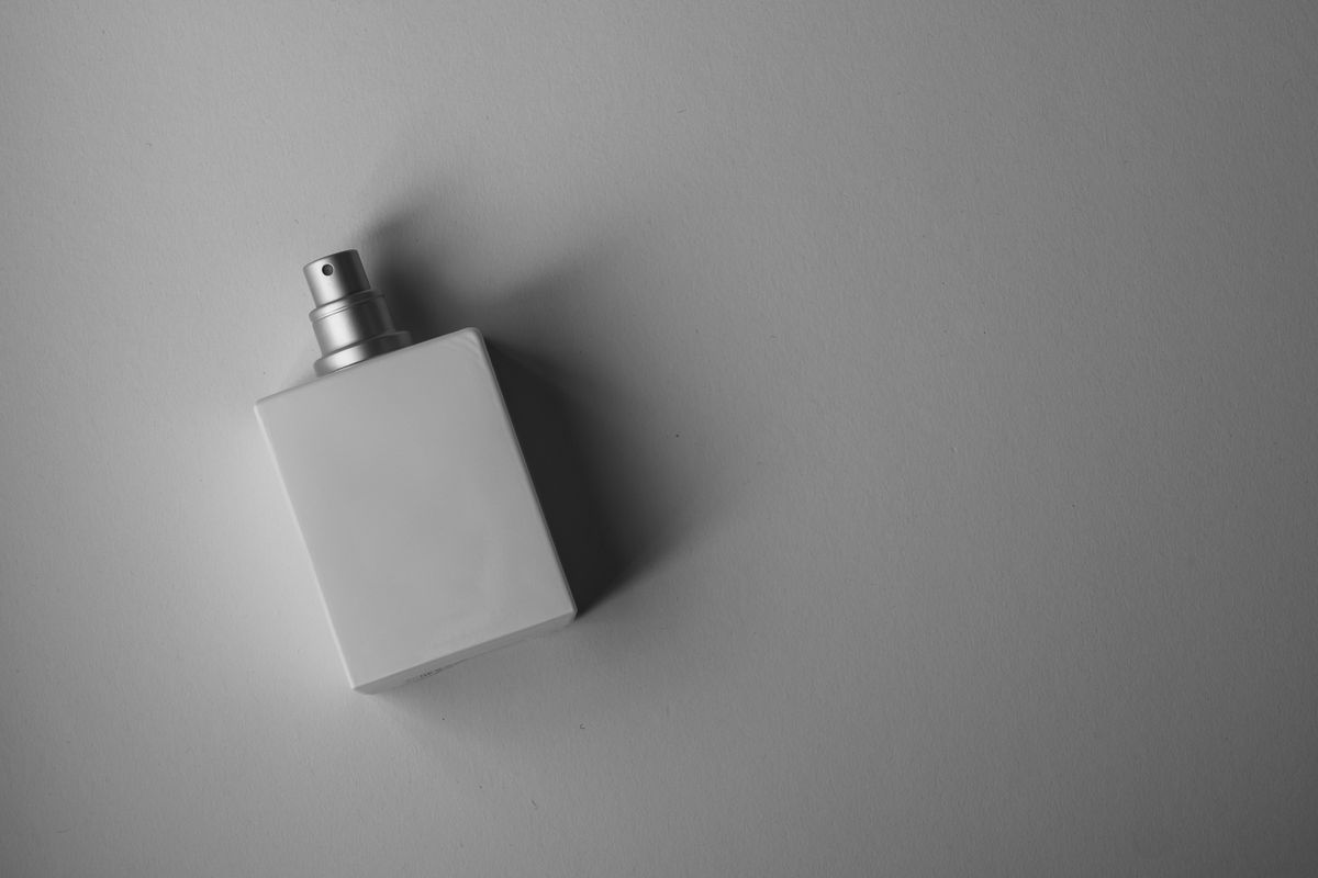 A simple white perfume bottle on a gray background.