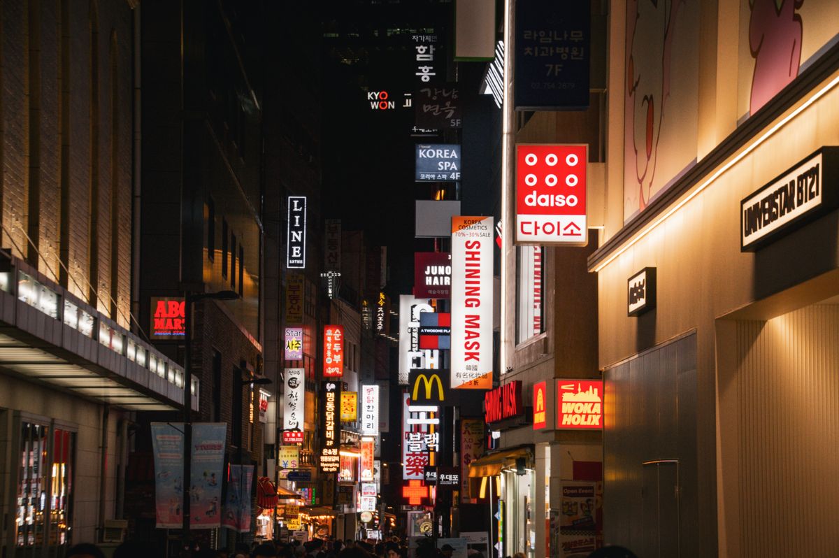 Korean beauty and wellness signs glowing on a Seoul shopping street at night.