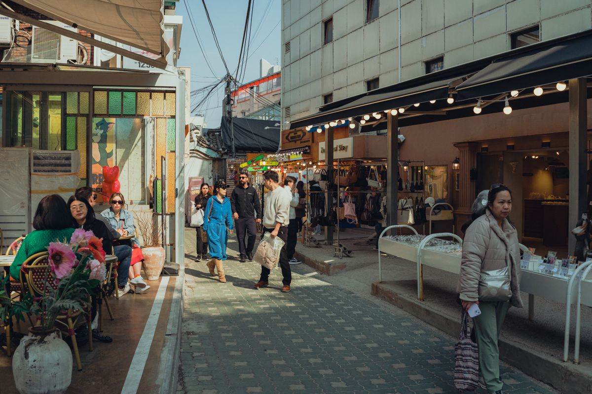 A lively Seoul shopping alley with small boutiques and street displays.