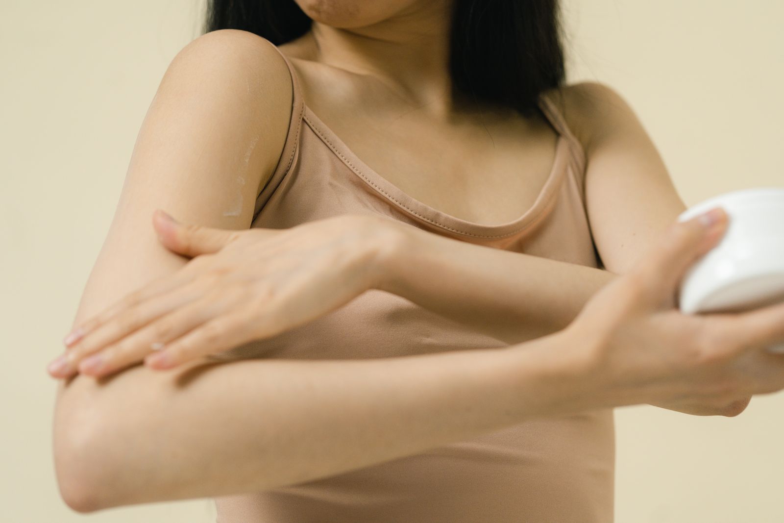 A woman applying moisturizer to her arm, showing the texture-focused side of body care.