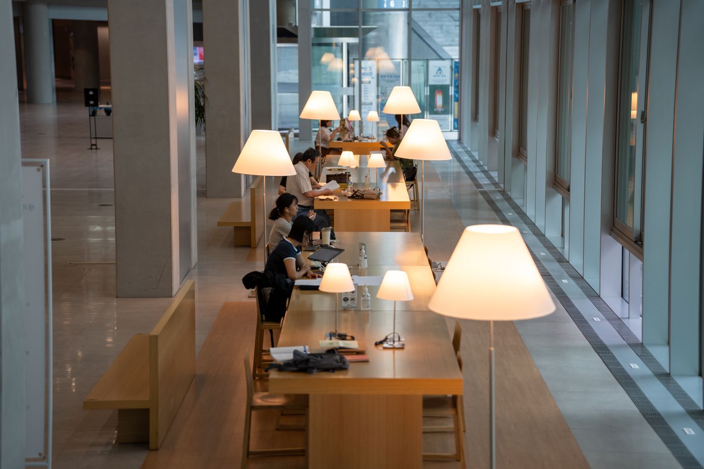 A warm library study area with tables and lamps, showing the quiet-work side of Korean focus culture.