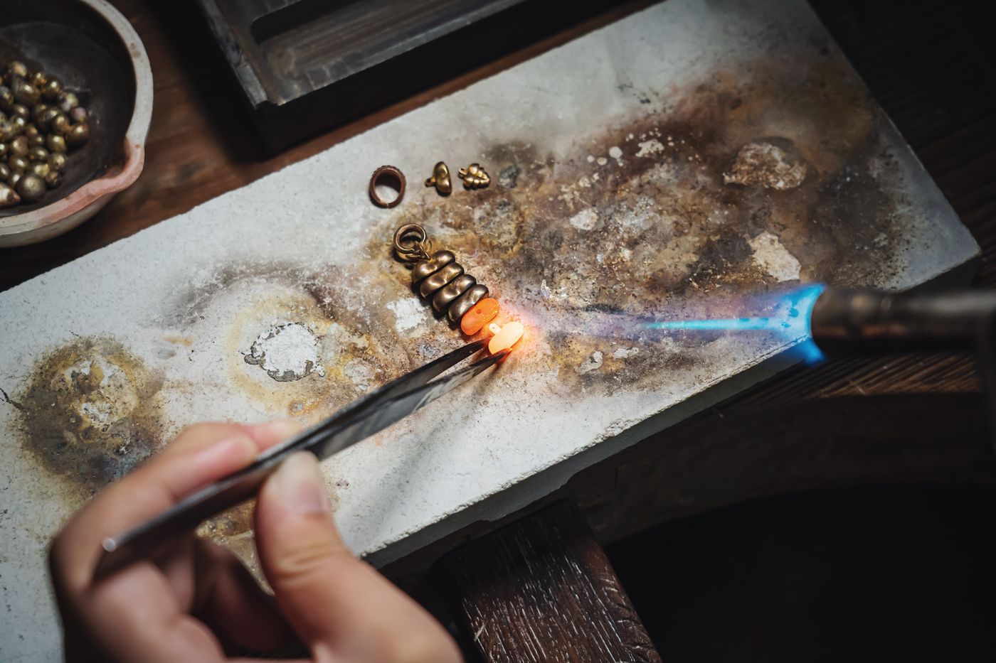 A jewelry artisan using a torch and tools, similar to the process behind silver ring workshops.