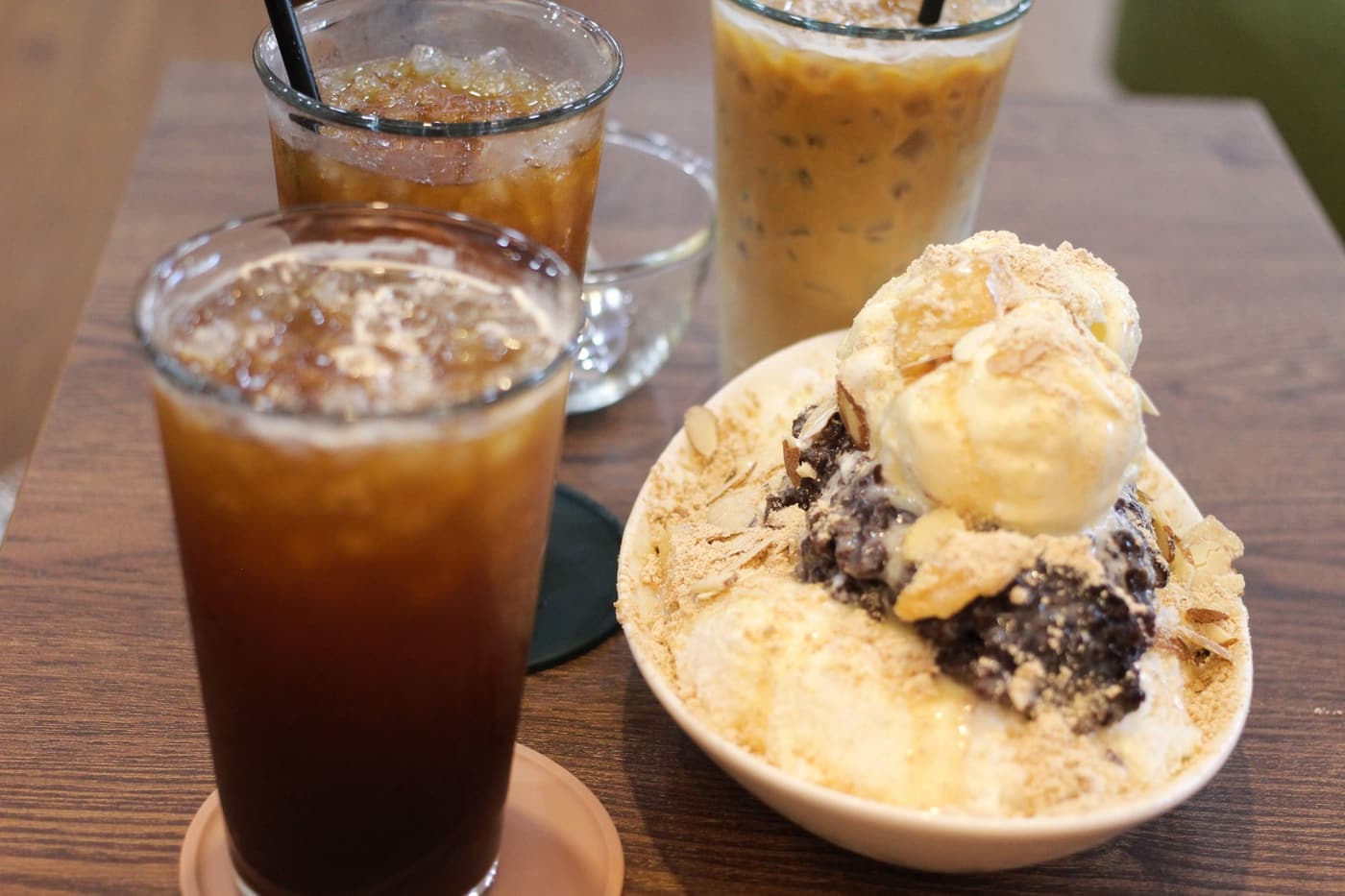 A bowl of bingsu on a cafe table beside a glass of iced coffee.