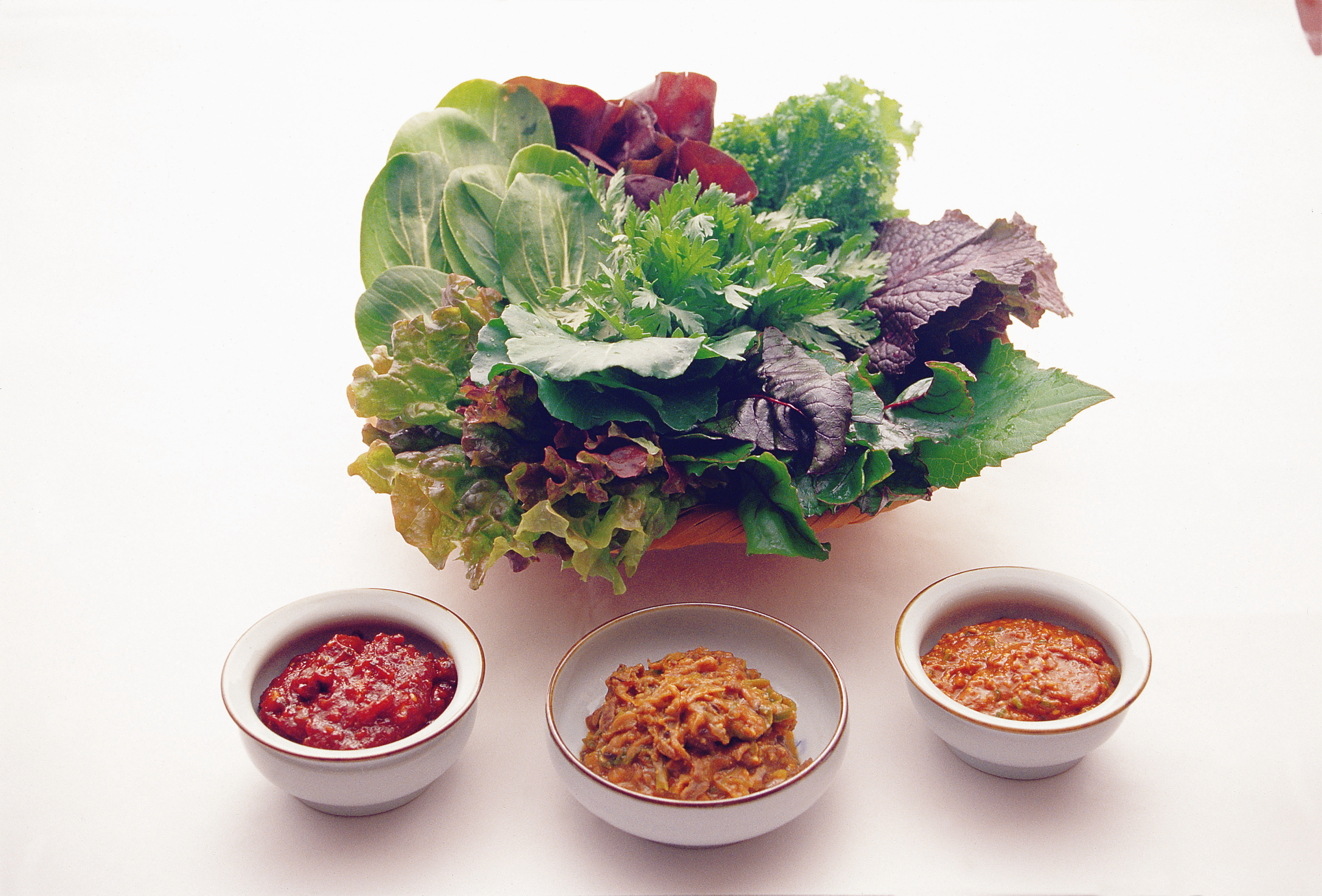 A platter of ssam vegetables and sauces arranged for Korean wraps.