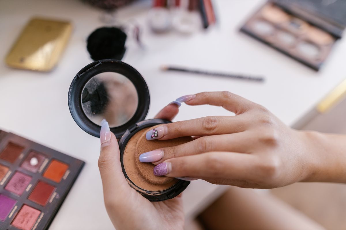 A compact puff applying complexion product during a makeup routine.