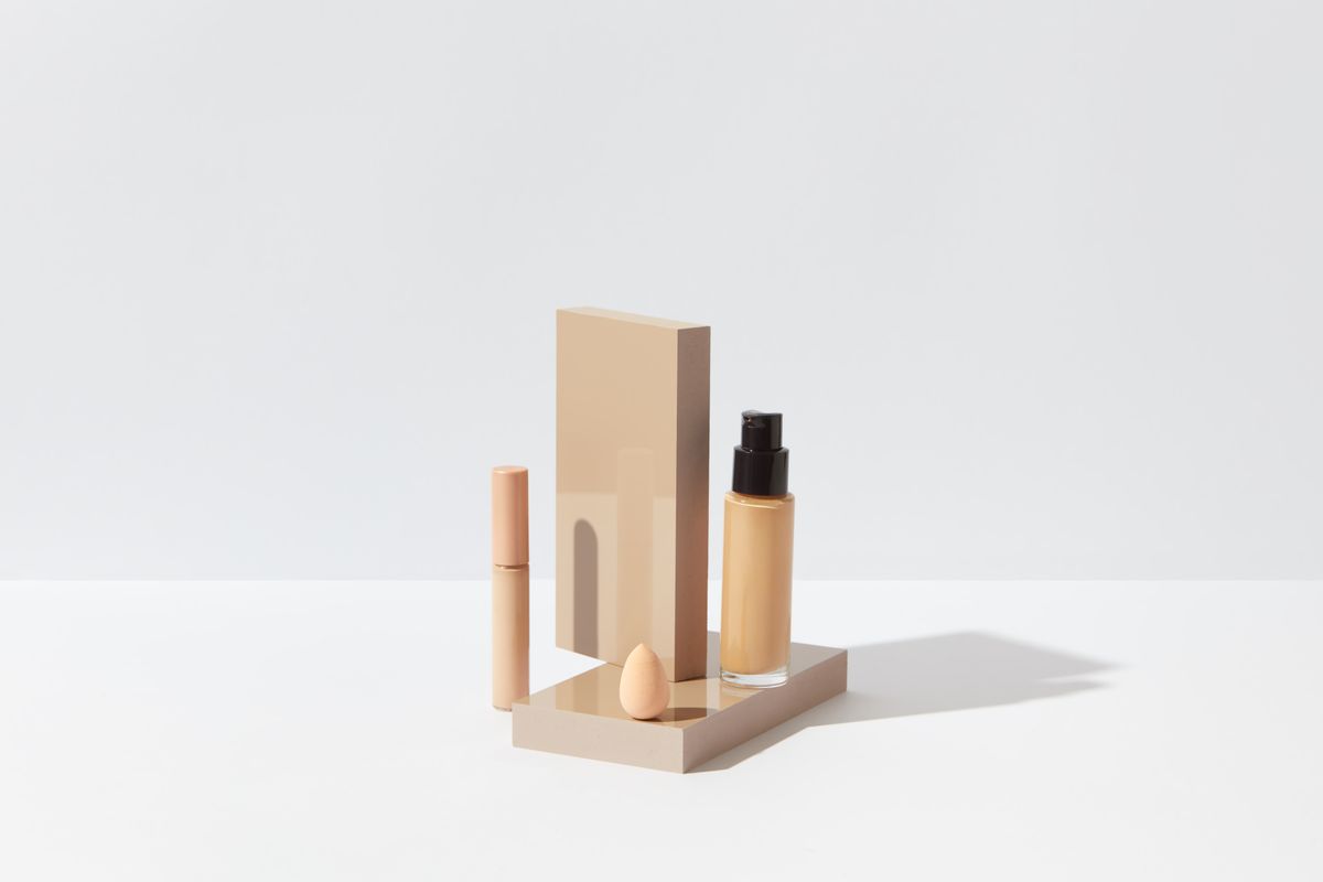 Foundation, concealer, and sponge arranged on a clean white surface.
