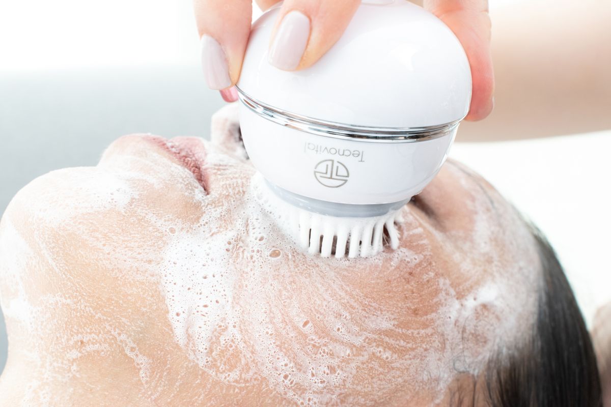 A cleansing brush being used with foam during a skincare routine.