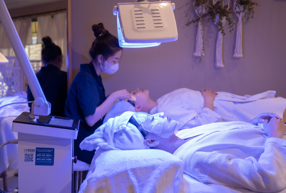 Clients receiving LED light therapy and facial treatment in a spa setting.