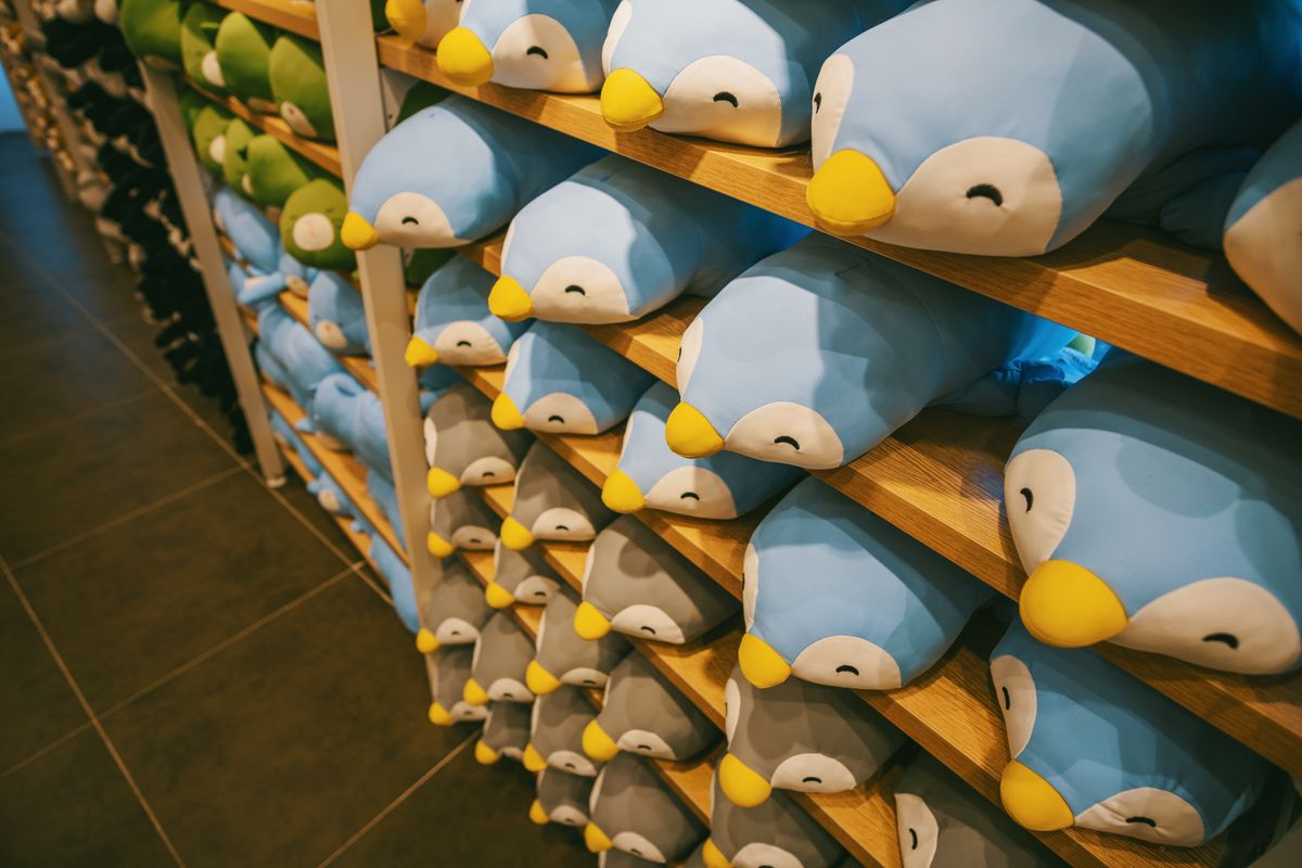 Rows of plush toys arranged on a wooden shelf.