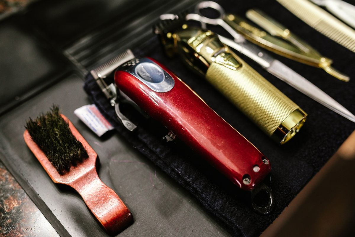 Barber tools including clippers and scissors arranged for a haircut.