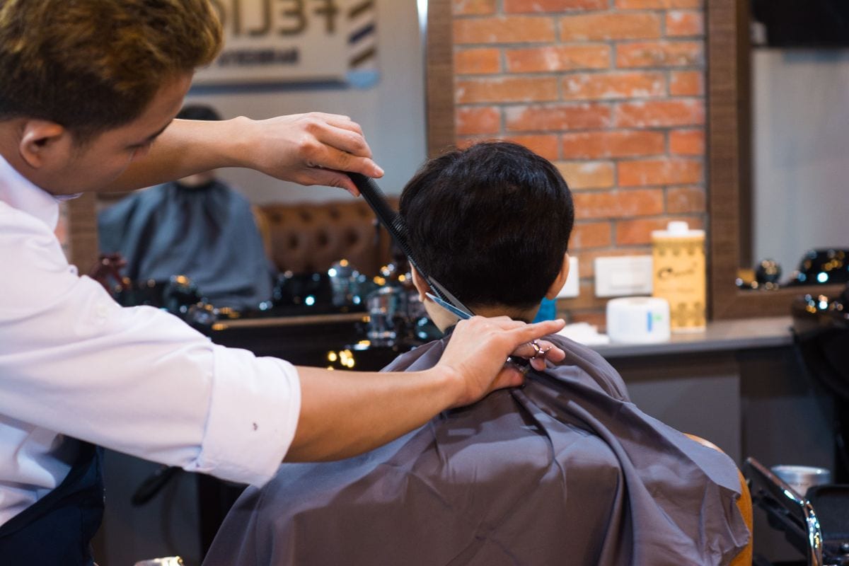 A stylist controlling the side and back hair during a real salon haircut