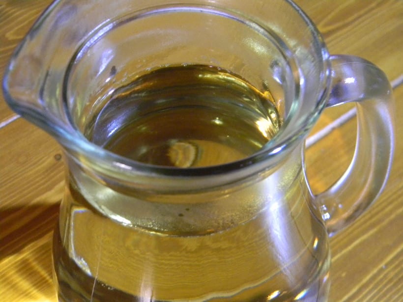 A glass pitcher of Korean oksusu-cha corn tea with a golden roasted color.