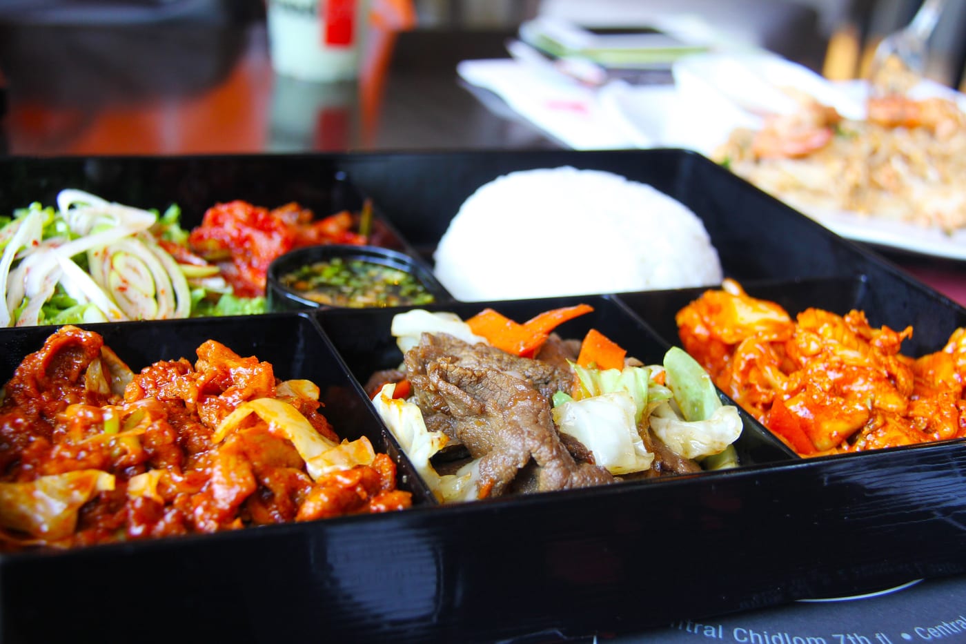 A Korean home-style dosirak meal with rice, side dishes, and metal utensils.