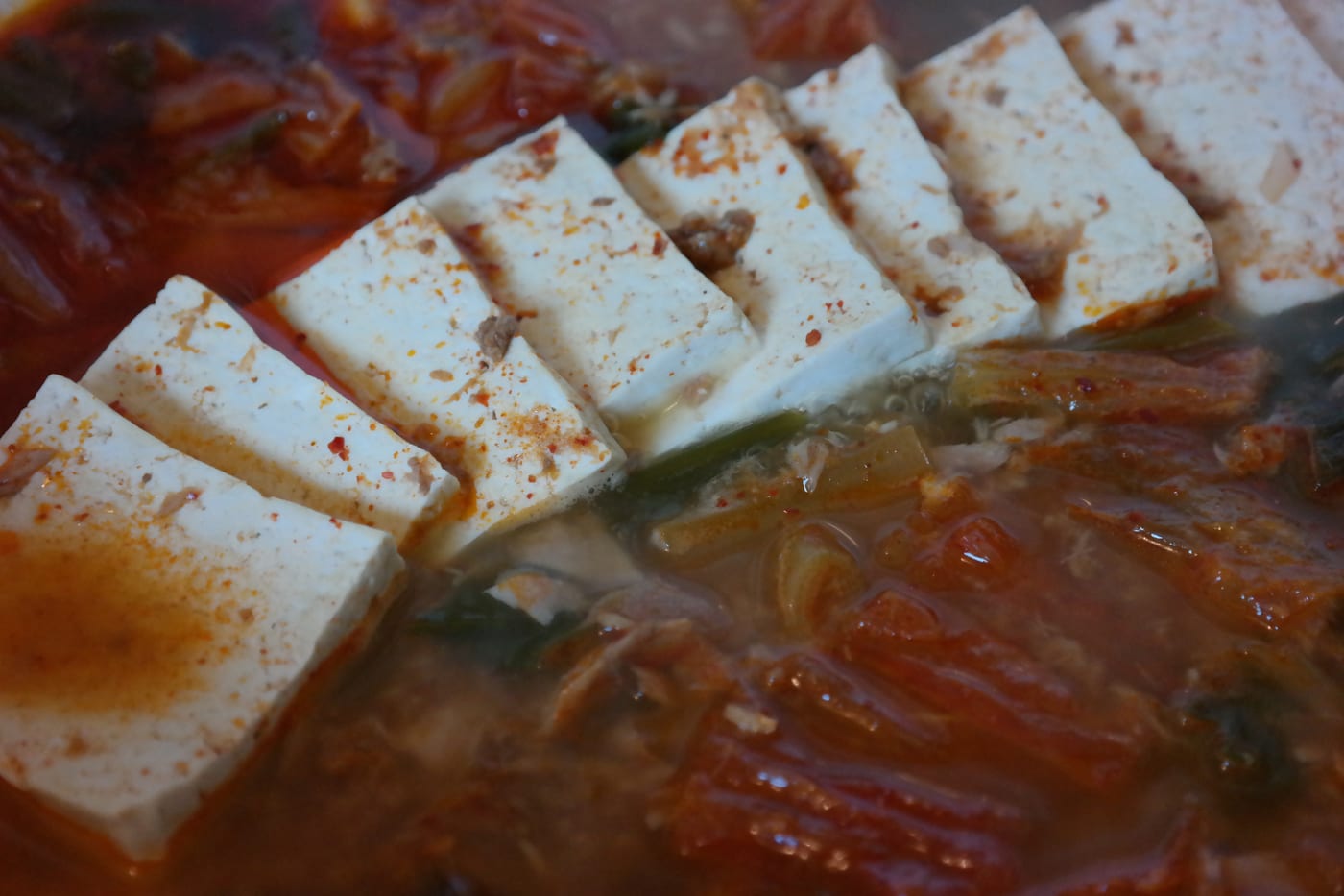 Kimchi jjigae with tofu in a red broth, showing a beginner-friendly stew structure.