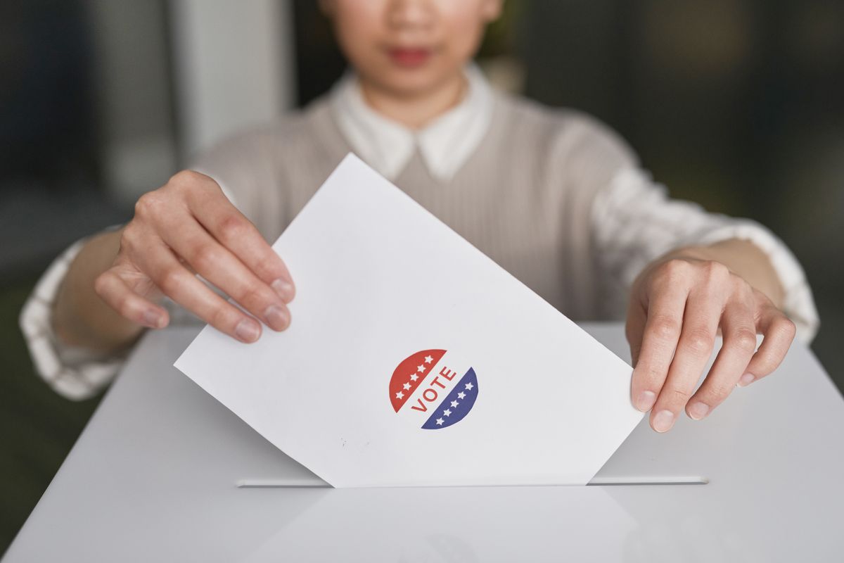 A voter places a ballot into a ballot box, representing South Korea's election cycle and party competition.