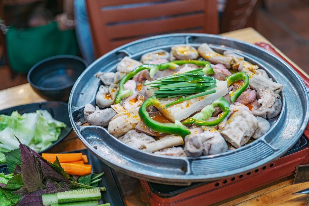 Meat and vegetables arranged around a real tabletop Korean barbecue grill