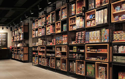 A wall of board games arranged on the official Red Button shelving system.