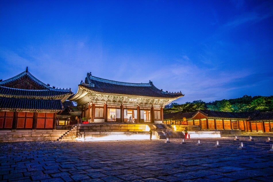 An illuminated hall and stone courtyard at Changgyeonggung during evening hours.