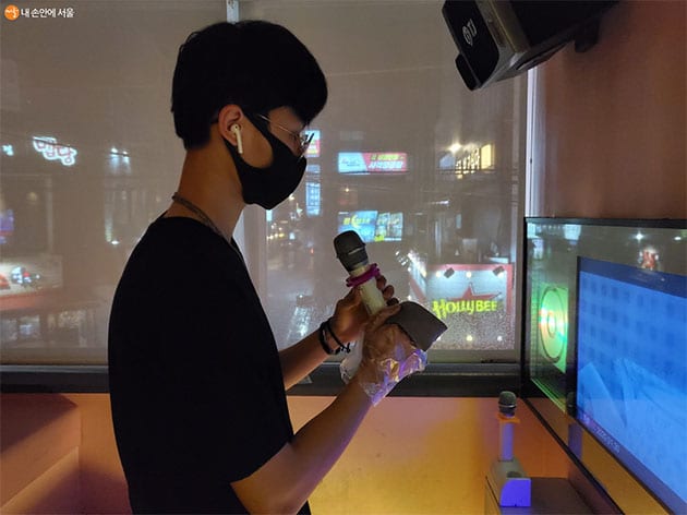A customer using the real touchscreen and microphone inside a Seoul coin noraebang room