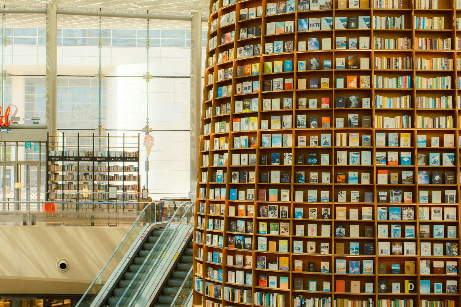 Towering curved bookshelves and an escalator inside Starfield Library at COEX Mall.