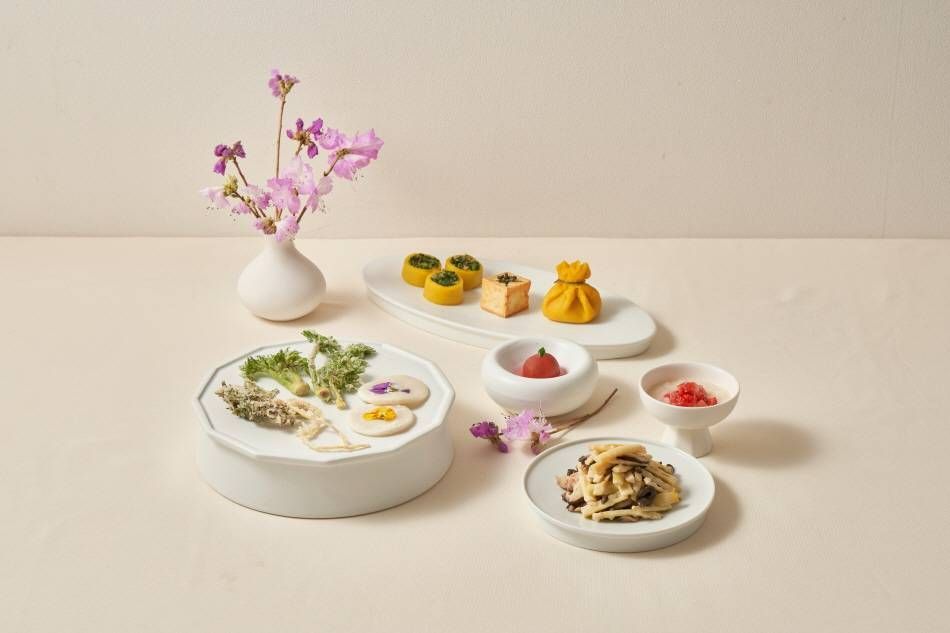 A refined Korean temple-food spread with mushrooms, greens, flower-shaped bites, and seasonal garnishes.
