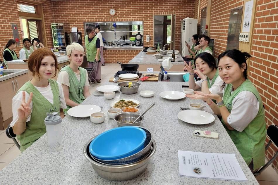 Participants preparing and tasting dishes during a Korean temple-food cooking program.