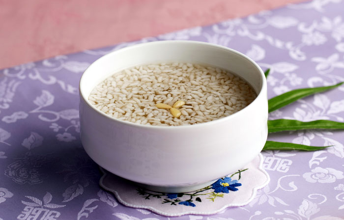 A bowl of chilled Korean sikhye with rice grains floating on the surface.
