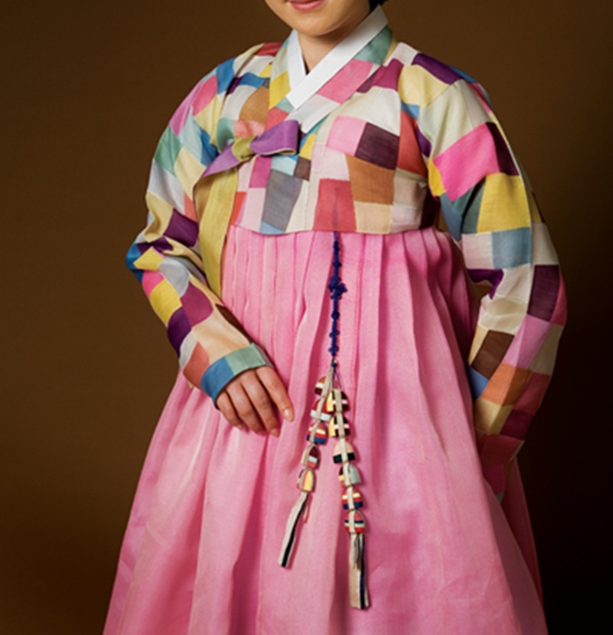 A model wears a contemporary patchwork textile with hanbok, showing how bojagi-inspired color can move into fashion.