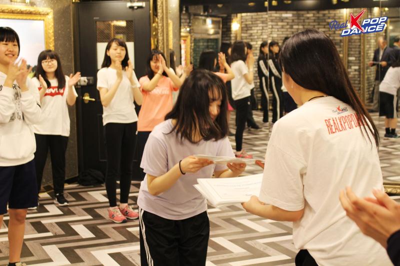 A student receives a Real K-pop Dance certificate after completing the Seoul class.