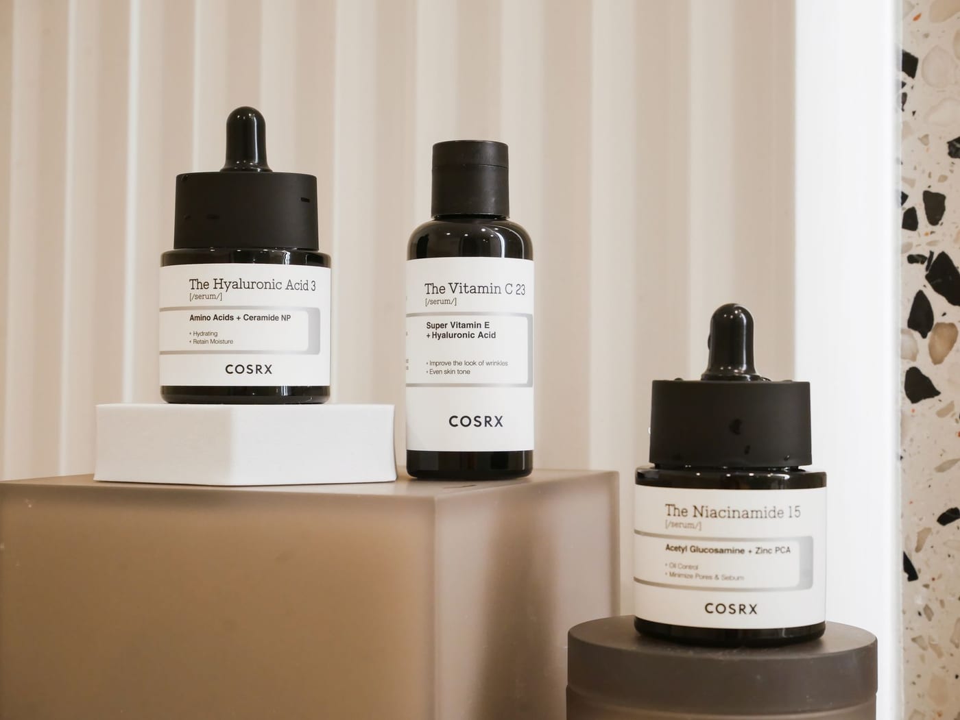 Three COSRX serum bottles labeled The Hyaluronic Acid 3, The Vitamin C 23, and The Niacinamide 15.
