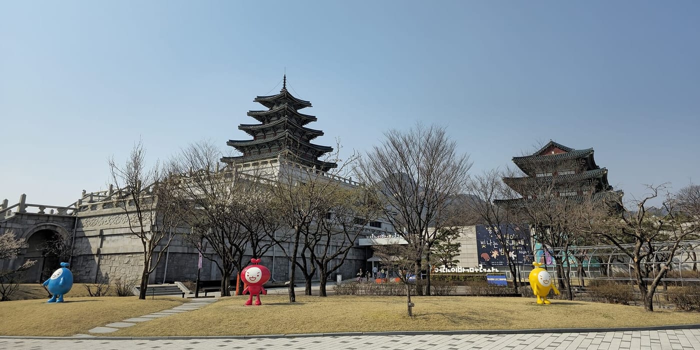 The National Folk Museum of Korea with colorful children's museum mascot statues on the lawn.