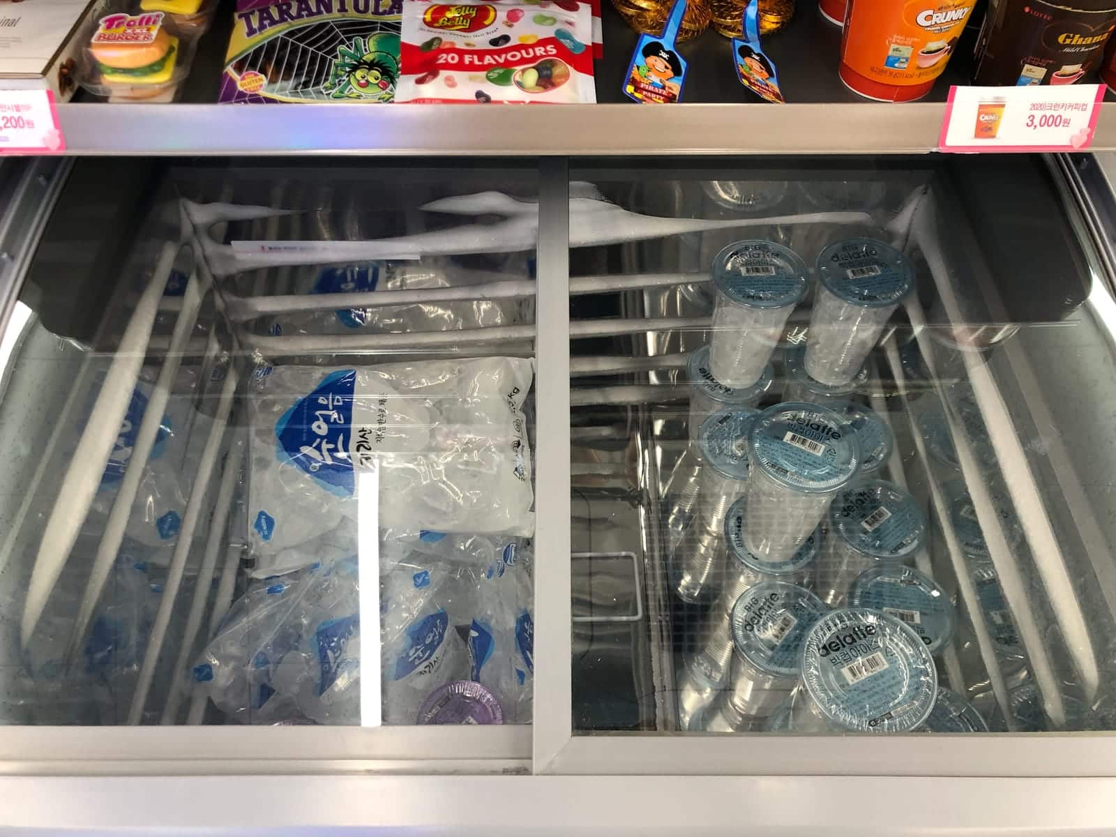 Inside a real CU convenience store freezer showing stacked plastic ice cups alongside candy.