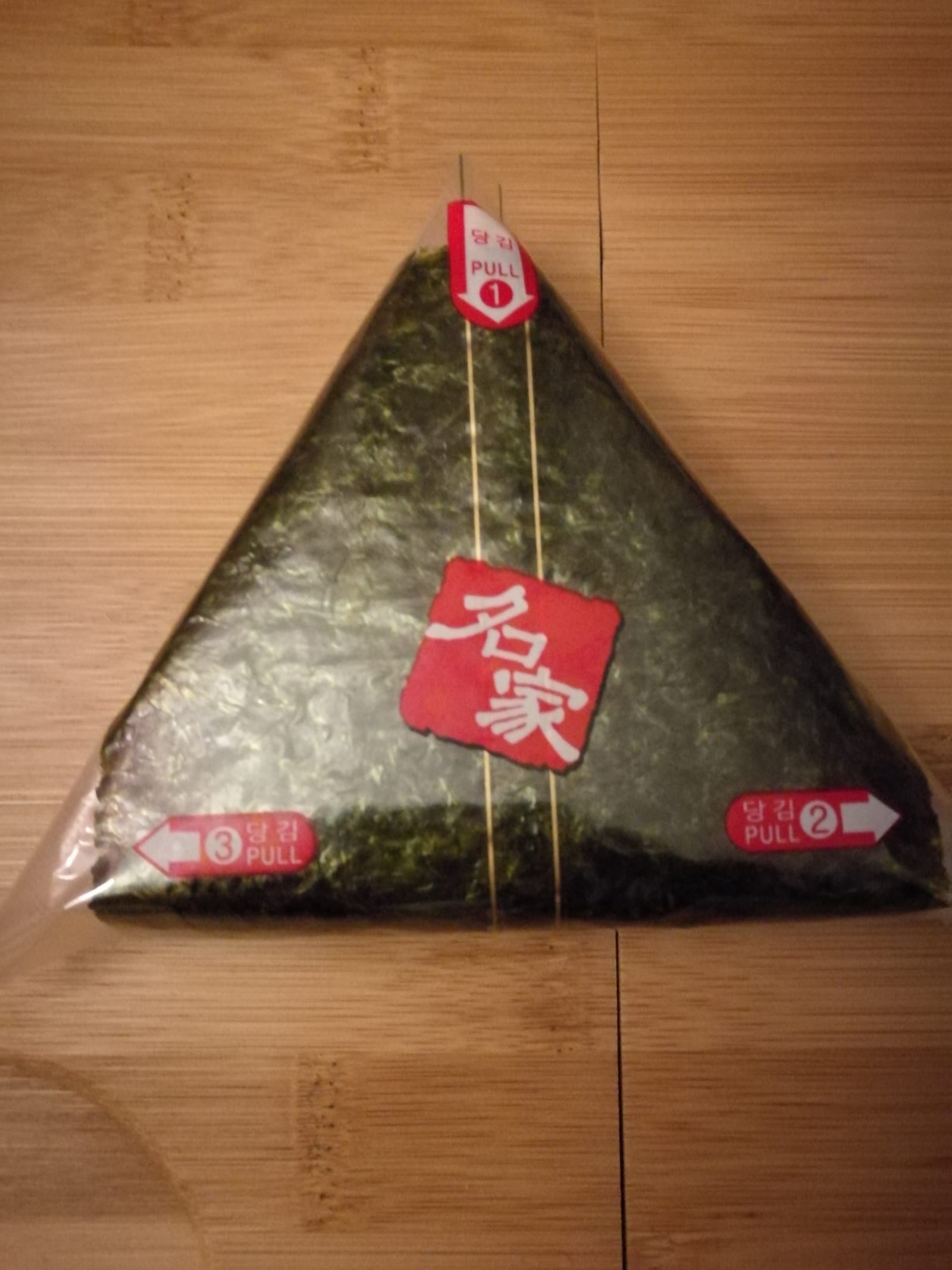 A Korean triangle gimbap in its wrapper.
