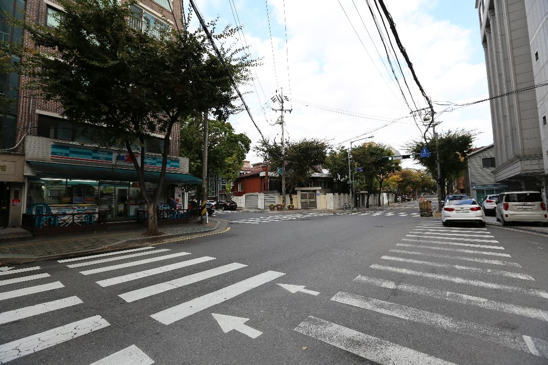 A Seoul street corner with a neighbourhood convenience store and its outdoor plastic tables.