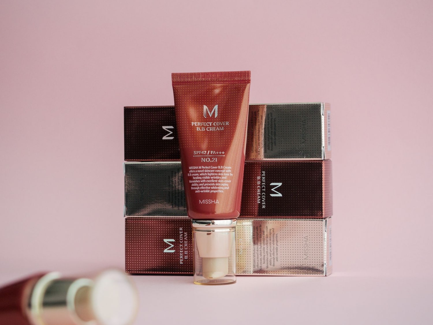 Real Korean skincare product photography: a BB cream tube, applicator, and stacked retail boxes with Korean-market packaging.