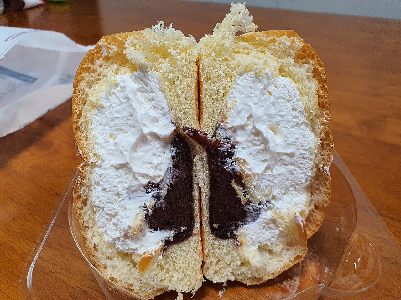Cross-section of Yonsei red bean cream bread showing white cream with a dark red bean core running through the centre.