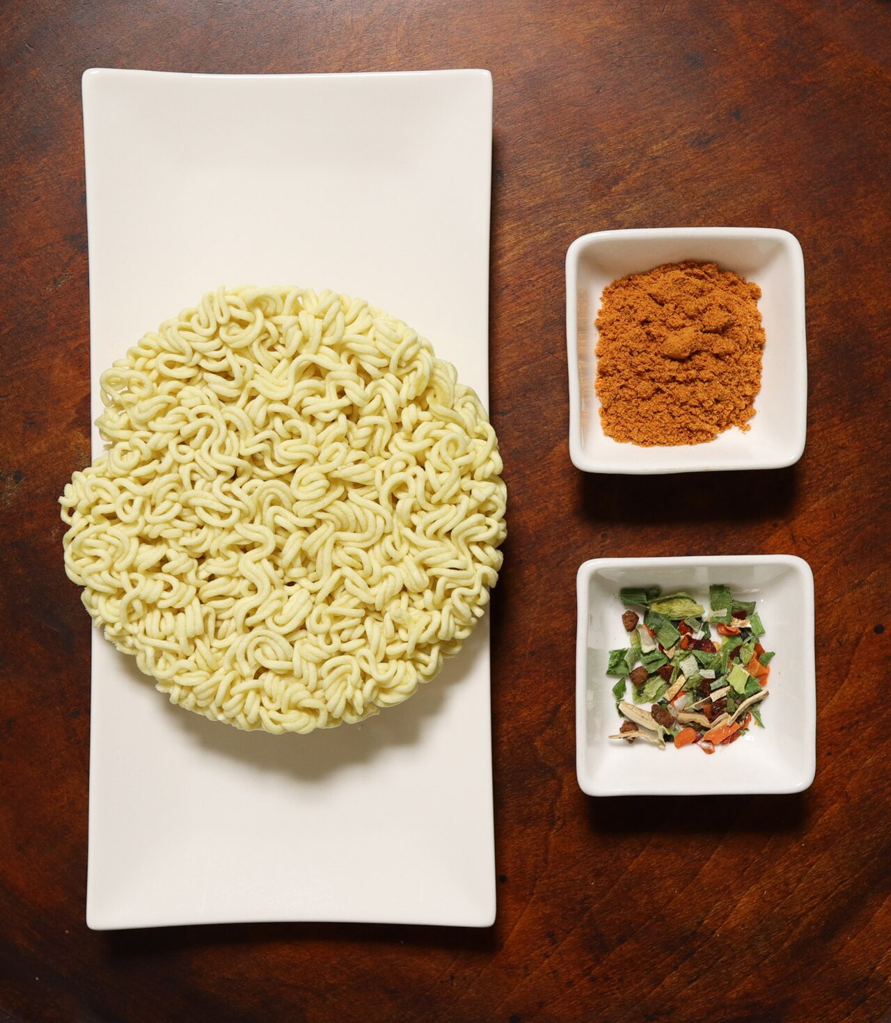 Shin Ramyun noodle block with its red-orange chili soup powder and a separate packet of dried vegetables.