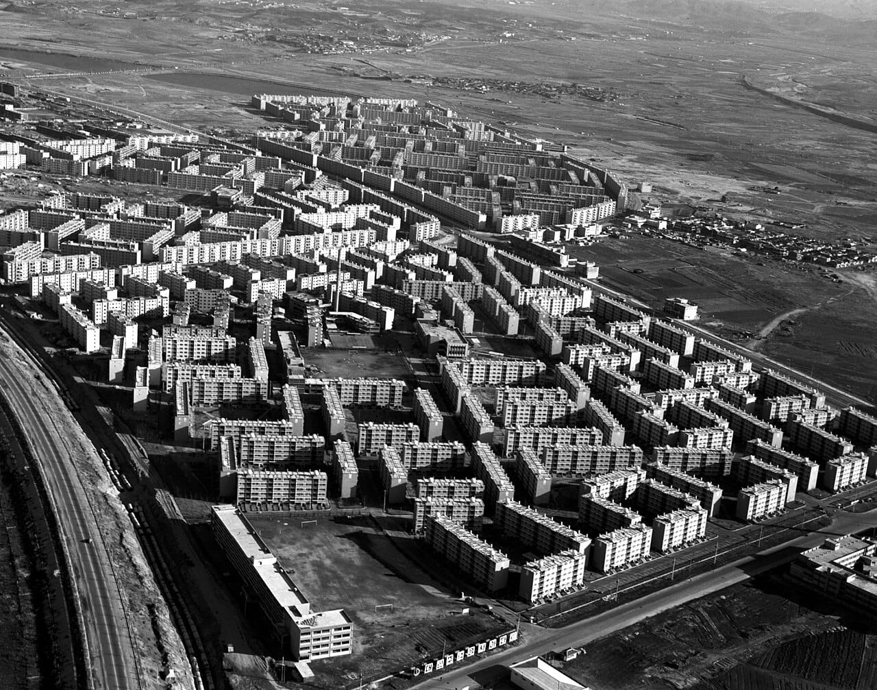 Aerial view of a vast Korean apartment estate in 1976, rows of blocks running out to bare land and fields.