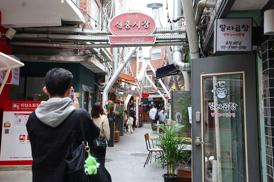 The Sinheung Market arch in Haebangchon, marked 1953, with cafes and restaurants down the lane behind it.