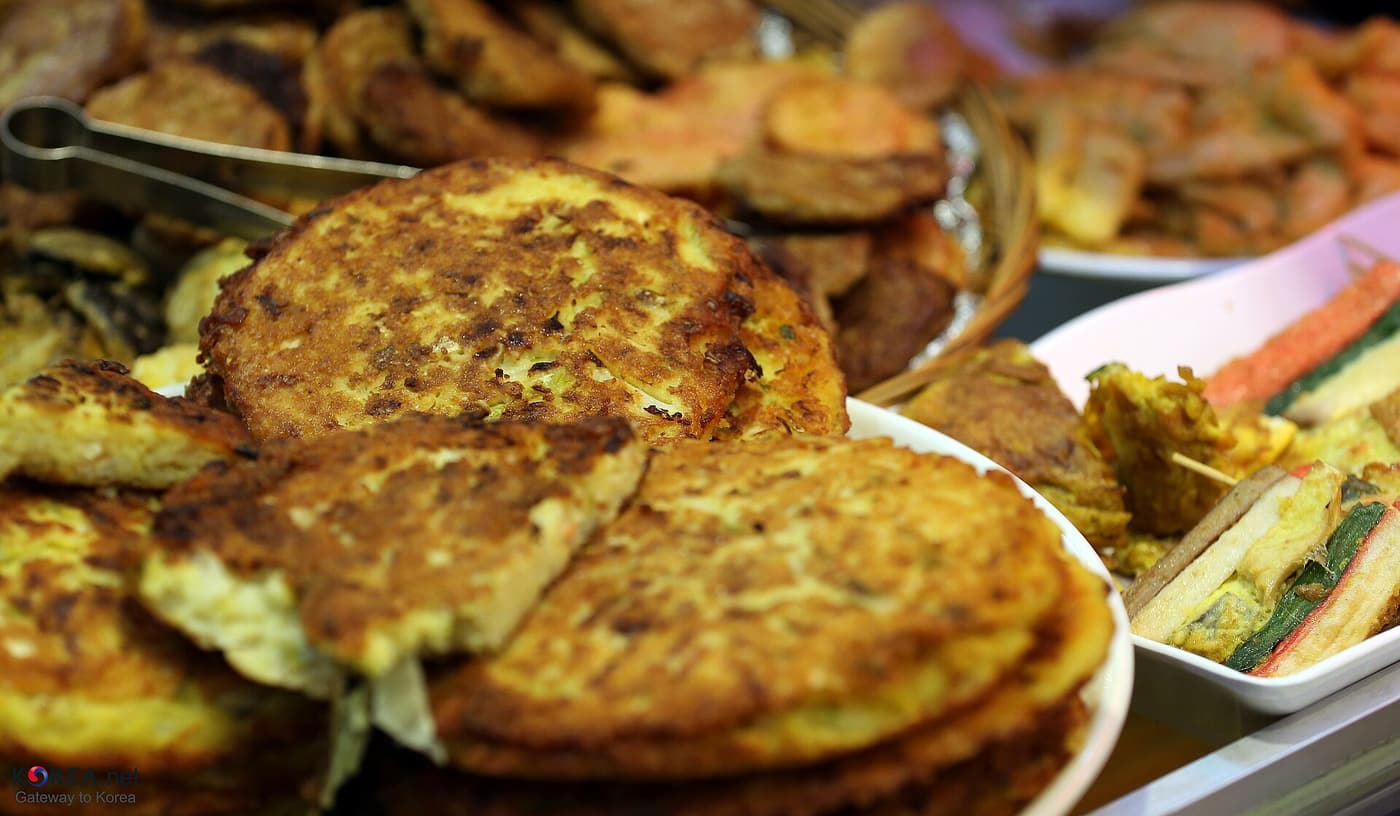 A food stall in Tongin Market with prepared dishes on trays.