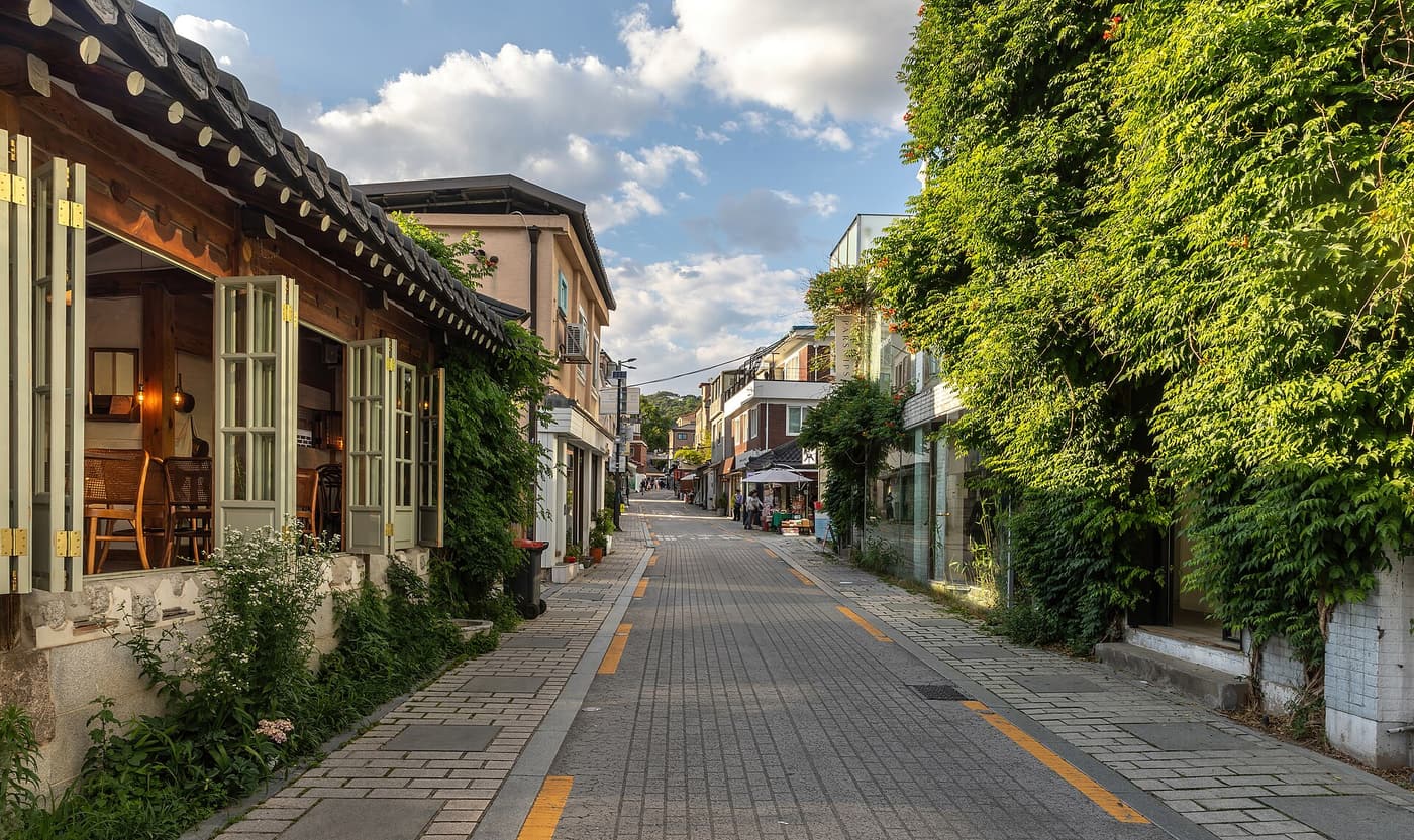 Gyedong-gil in Bukchon at golden hour, climbing plants over a low wall.