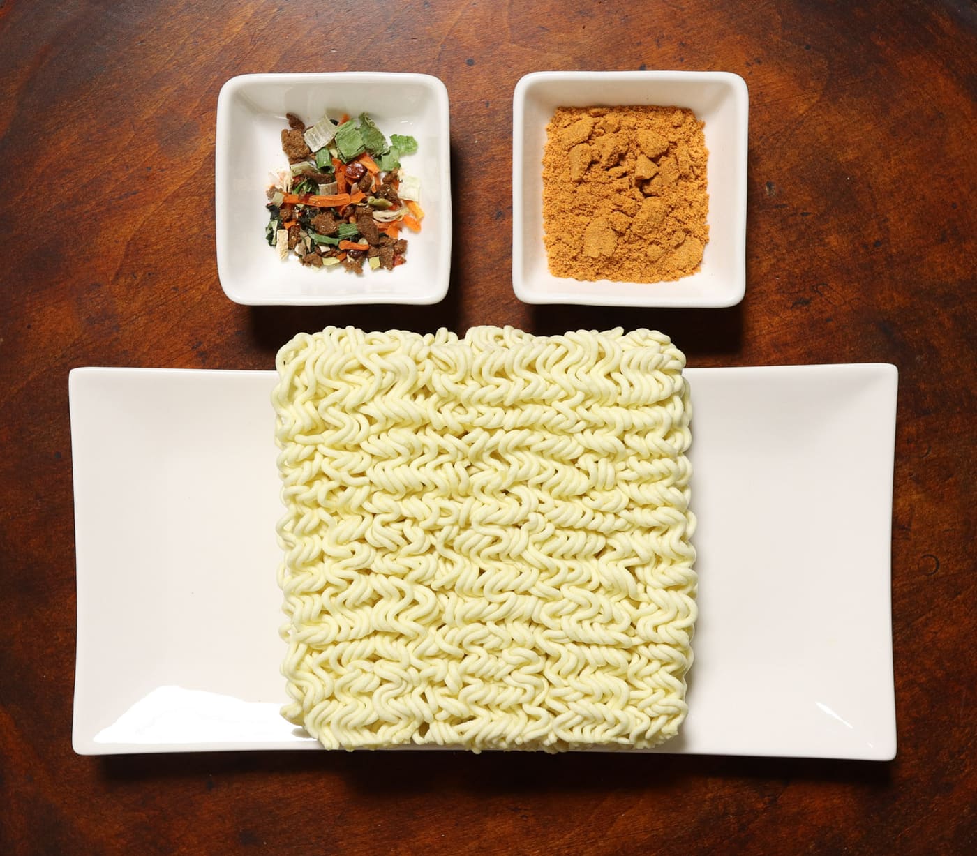 Contents of a Jin Ramen spicy packet, with a distinctly orange-red soup powder.