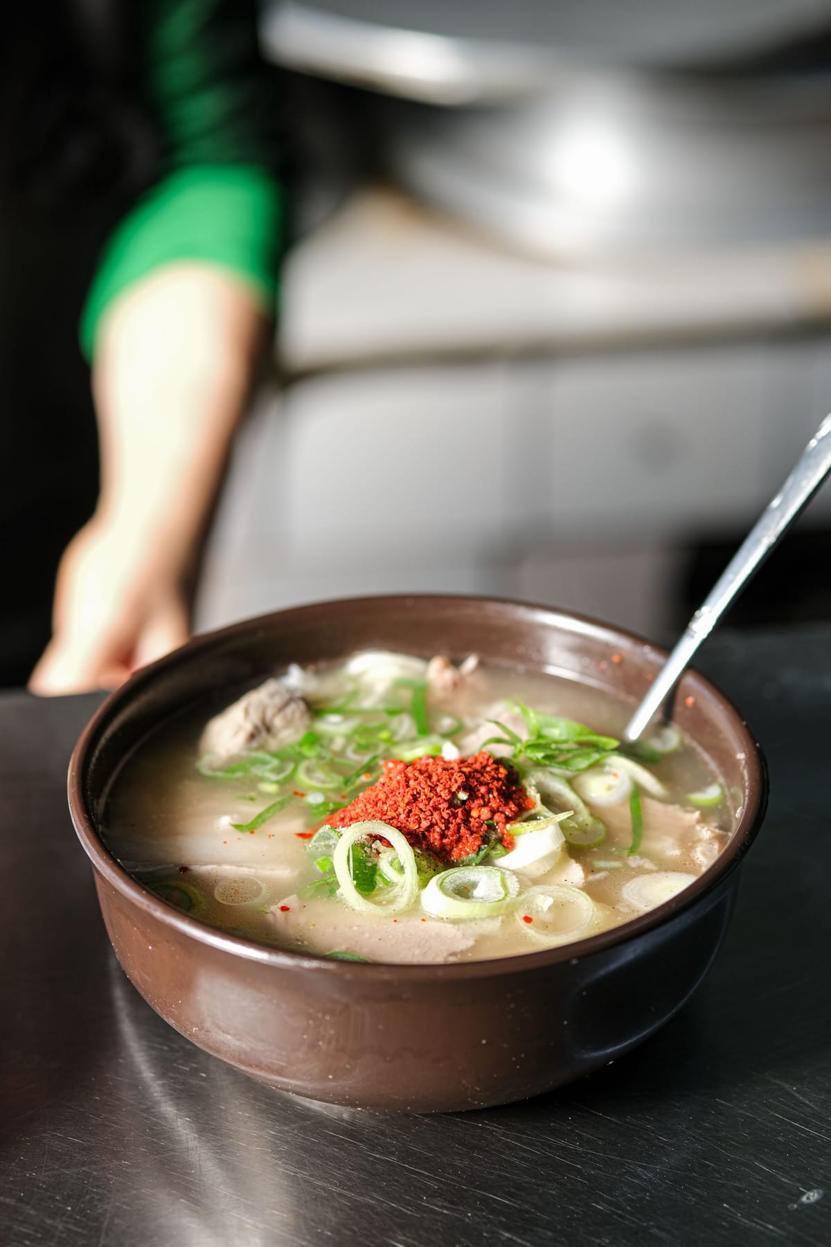 A Korean beef soup served with rice and side dishes on a wooden table.