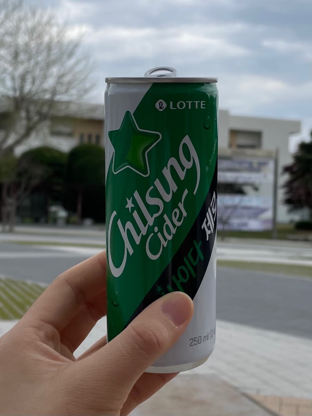 A hand holding a 250 ml can of Chilsung Cider Zero in green, white and black.