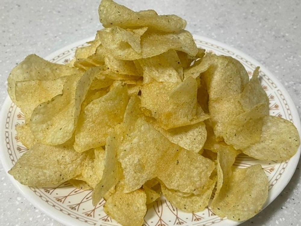 A plate of Pocachip — thin, flat, pale-gold chips with visible seasoning specks.