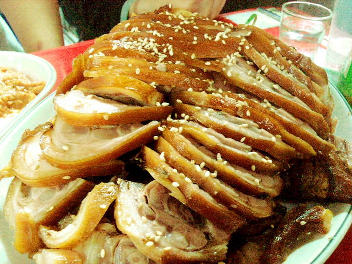 A platter of sliced jokbal, dark and glossy, scattered with sesame seeds.